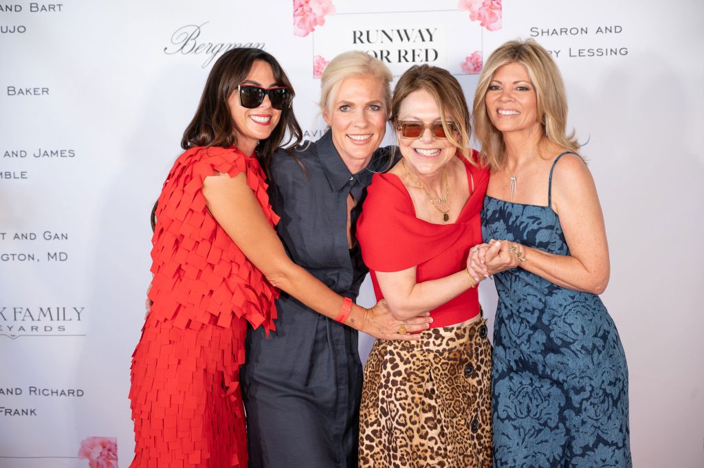 Four smiling women pose together on the red carpet at the Runway for Red heart health fundraiser in Napa Valley.