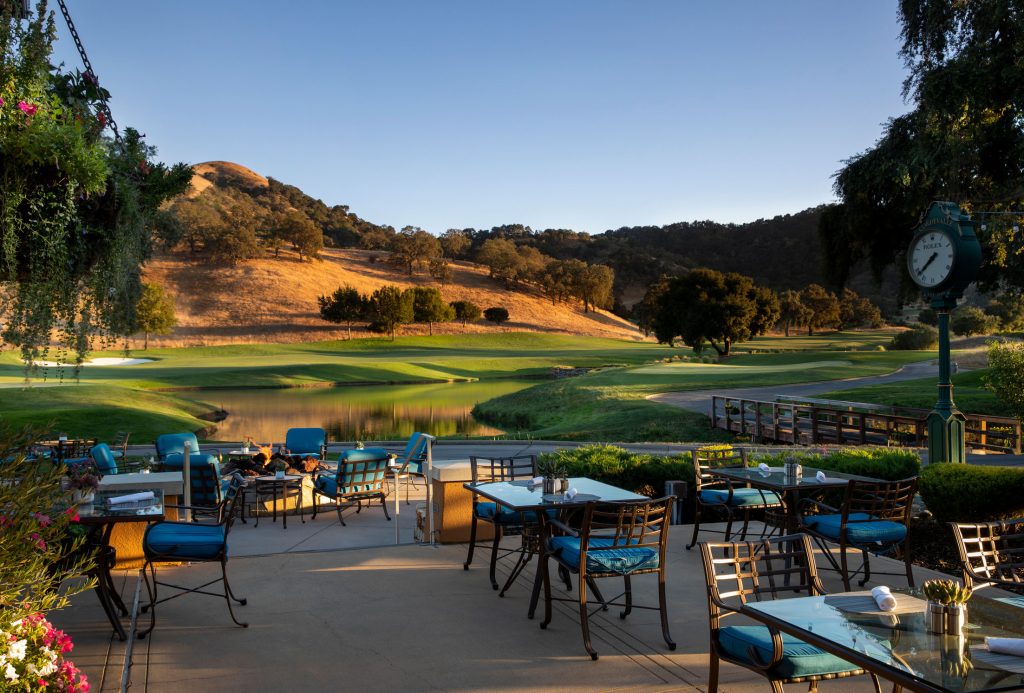 Scenic outdoor dining area by the lake at CordeValle with panoramic views of the golf course and golden California hills.