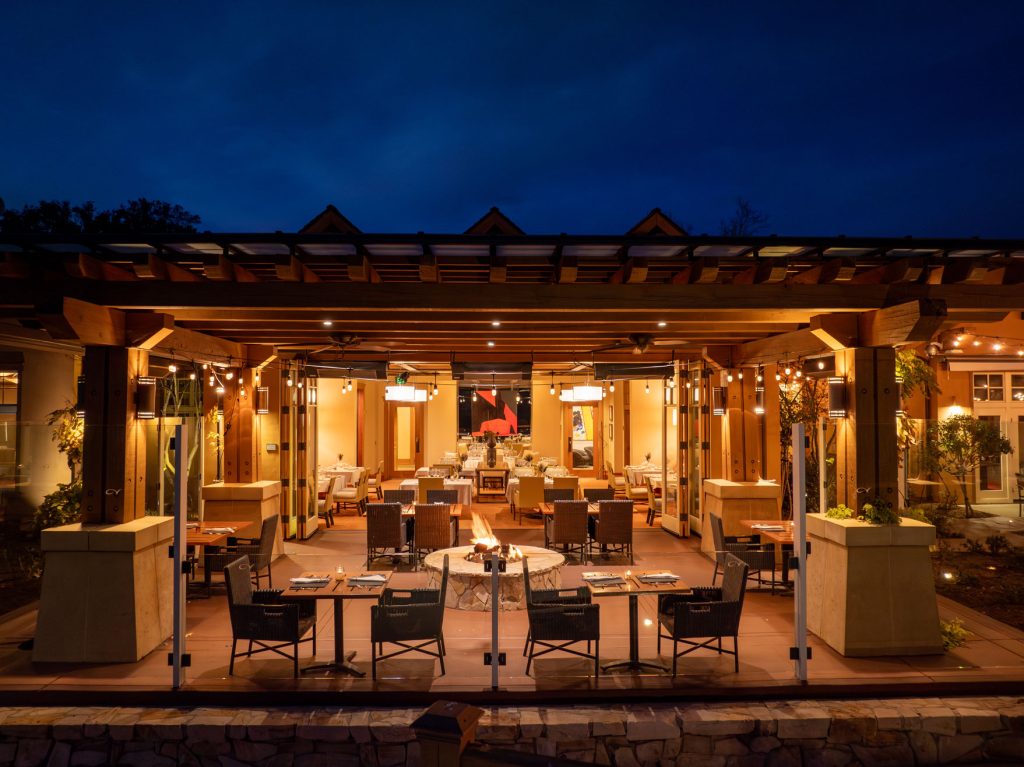 Romantic evening dining at CordeValle with glowing lights, cozy seating, and a warm firepit centerpiece.