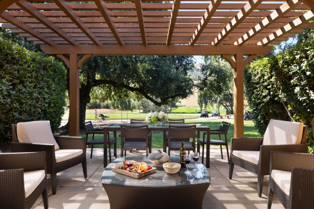 Outdoor lounge and dining setup at CordeValle under a wooden pergola, perfect for wine and charcuterie with a view.