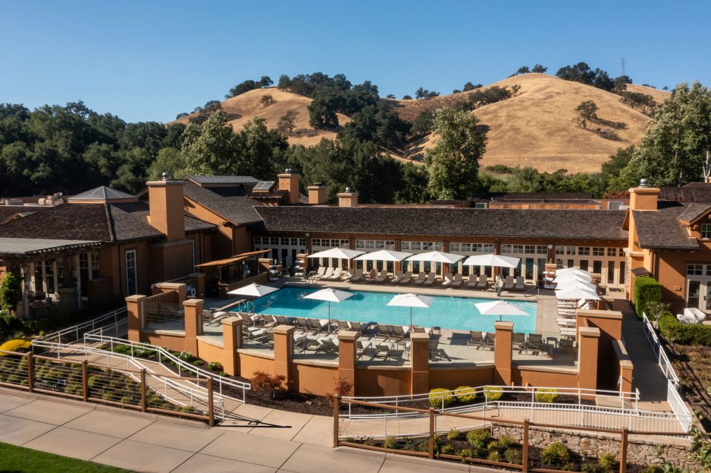 Expansive pool area at CordeValle with sun loungers and umbrellas, surrounded by golden California hills for a serene retreat.