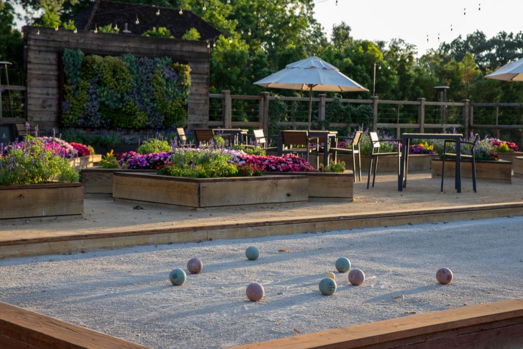 Charming outdoor bocce ball court at CordeValle surrounded by colorful flower beds and cozy seating areas.