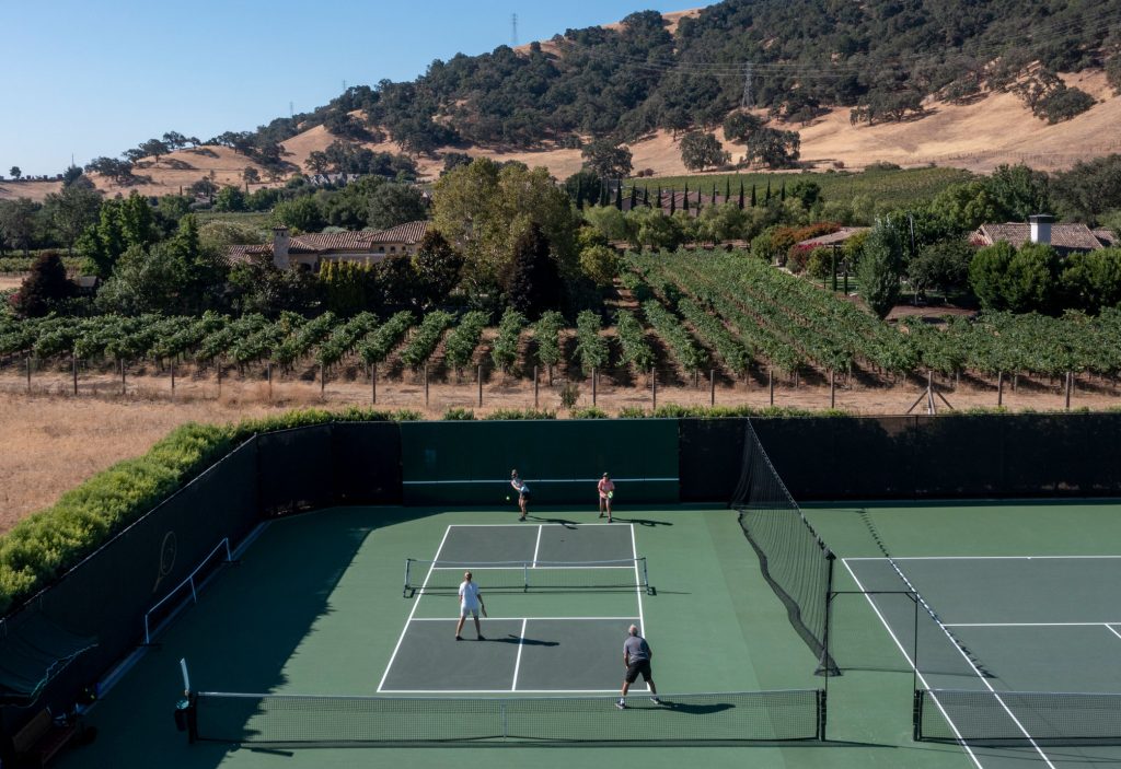 Guests enjoying a game of pickleball at CordeValle with scenic vineyard views and golden hills in the background.