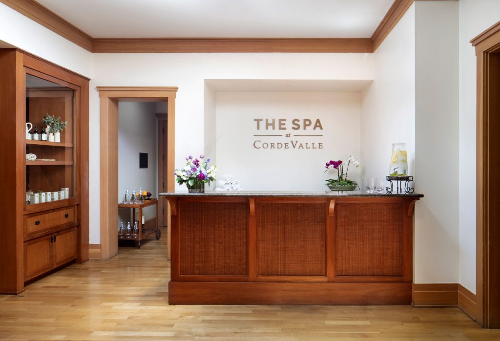 Welcoming spa reception at CordeValle featuring warm wood décor, fresh flowers, and refreshing infused water.