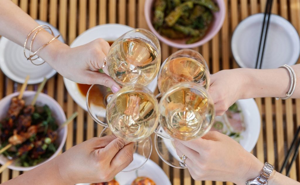Guests toasting with wine at restaurant at Four Seasons Resort and Residences Napa Valley.